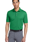 Man wearing a green polo shirt and gray pants on a white background