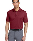 Man wearing a maroon polo shirt and gray pants on a white background