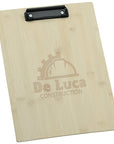A light natural wood clipboard with a black metal clip at the top and an engraved logo for 'De Luca Construction' on the front, shown against a plain white background.
