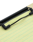 A black plastic clip-on document holder with a curved wire support, shown holding a sheet of lined paper on a light wood surface against a white background.
