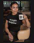 Woman wearing a black t-shirt with motivational text, holding a mug in a casual setting.