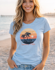 Woman wearing a light blue t-shirt with a beach graphic and 'Summer Vibes' text on a beach.