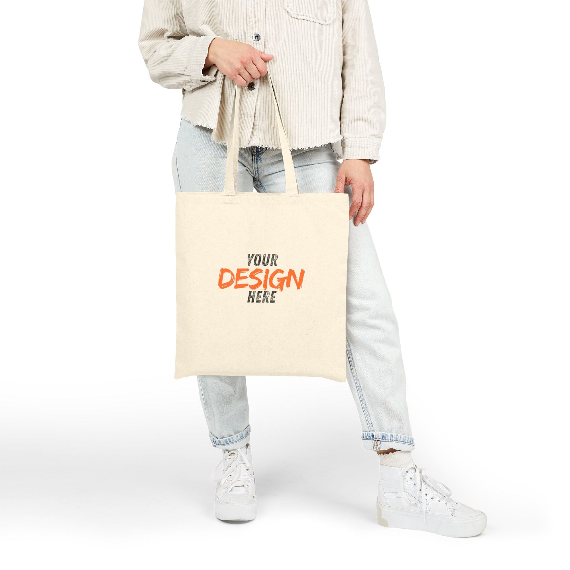 Person holding a beige tote bag with 'Your Design Here' text on a white background