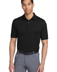 Man wearing a black polo shirt and gray pants on a white background
