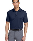 Man wearing a navy polo shirt and gray pants on a white background