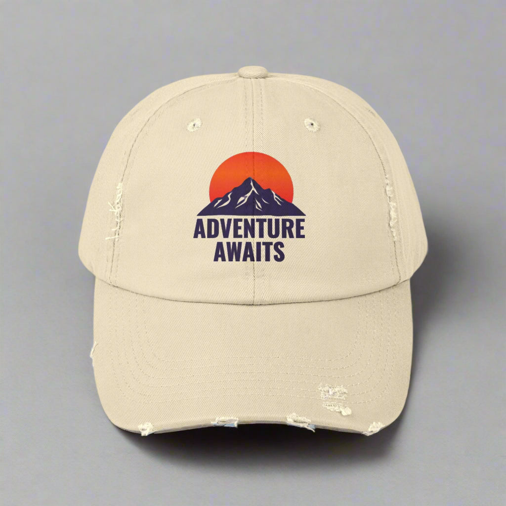 Beige cap with 'Adventure Awaits' design on a white background