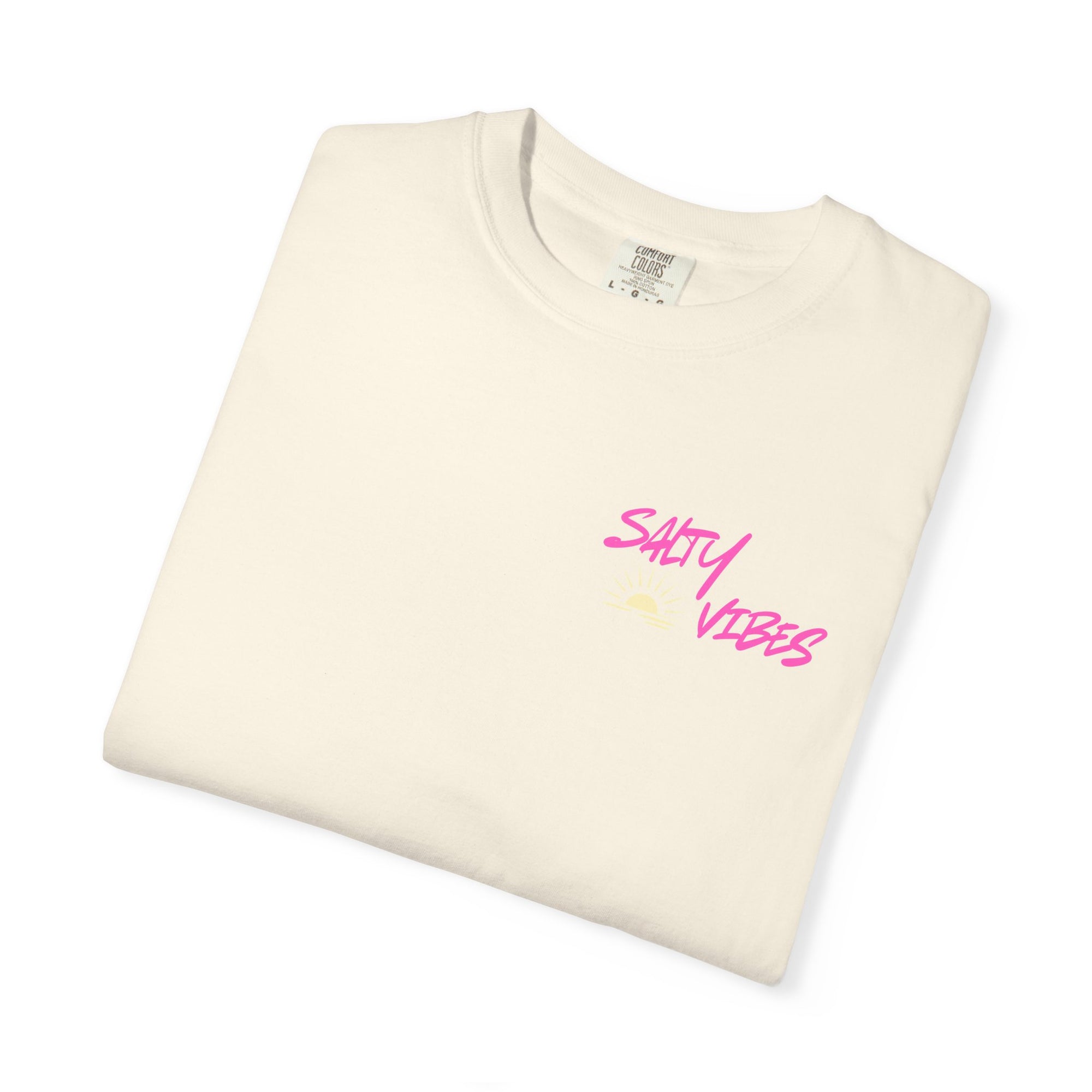 Folded cream-colored t-shirt with 'Salty Vibes' text in pink on a white background