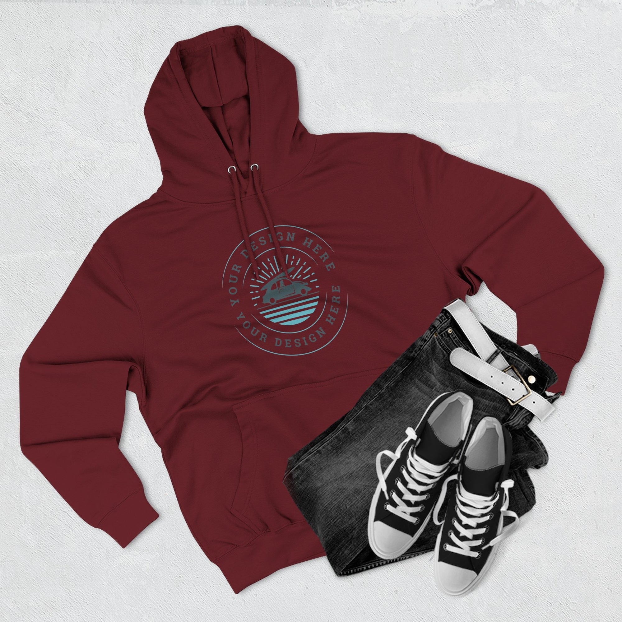 Maroon hoodie with a logo, black jeans, and black sneakers on a light gray background