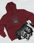 Maroon hoodie with a logo, black jeans, and black sneakers on a light gray background