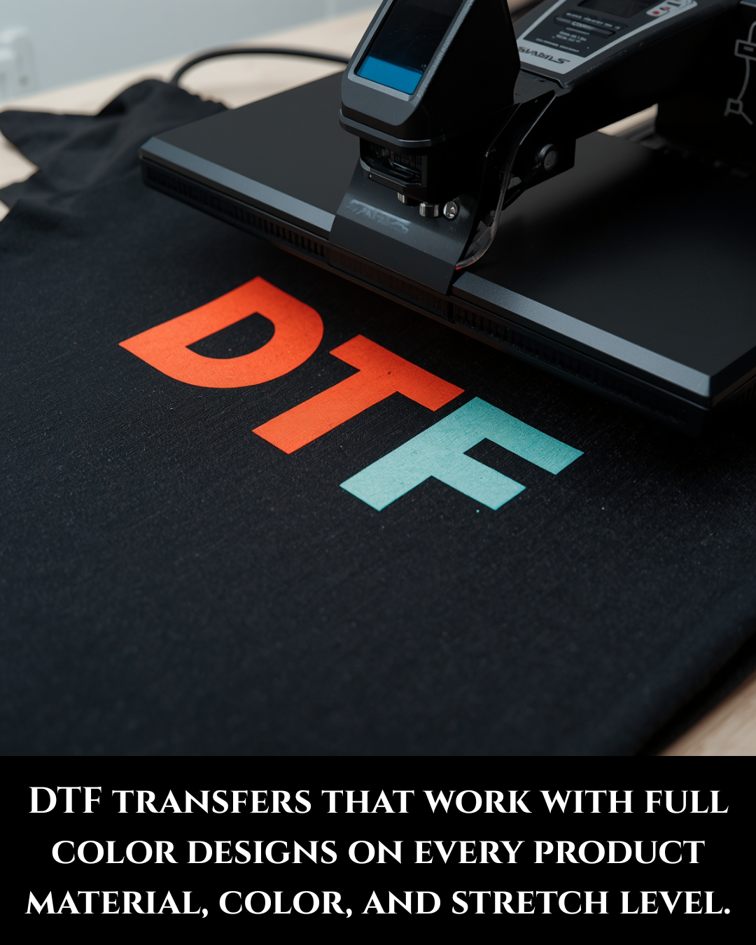 Black t-shirt with 'DTF' printed in orange and green on a heat press machine.