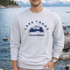 Person wearing a gray sweatshirt with 'Lake Tahoe California' print, standing by a lake.