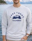 Person wearing a gray sweatshirt with 'Lake Tahoe California' print, standing by a lake.